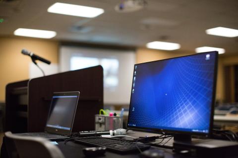 Operating computer at the presenter's table next to the podium.