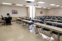 Large classroom with tables and chair facing forward.