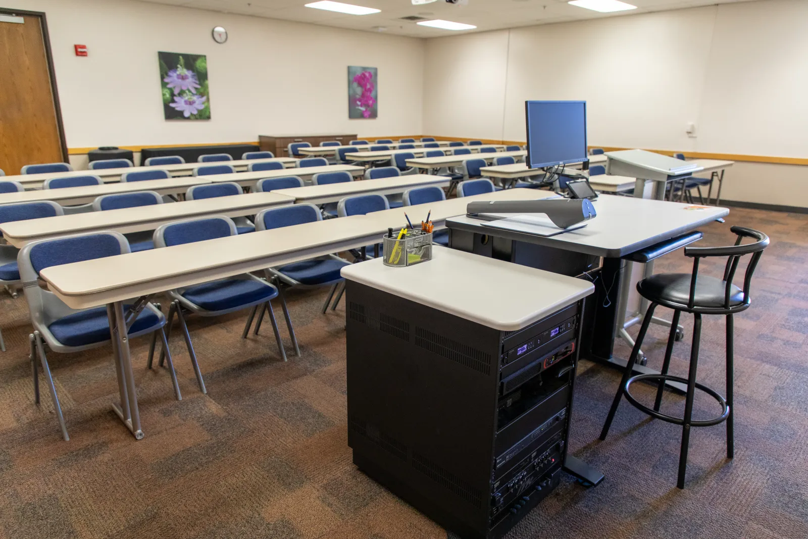 Lecture hall with rows of chairs and tables facing a podium