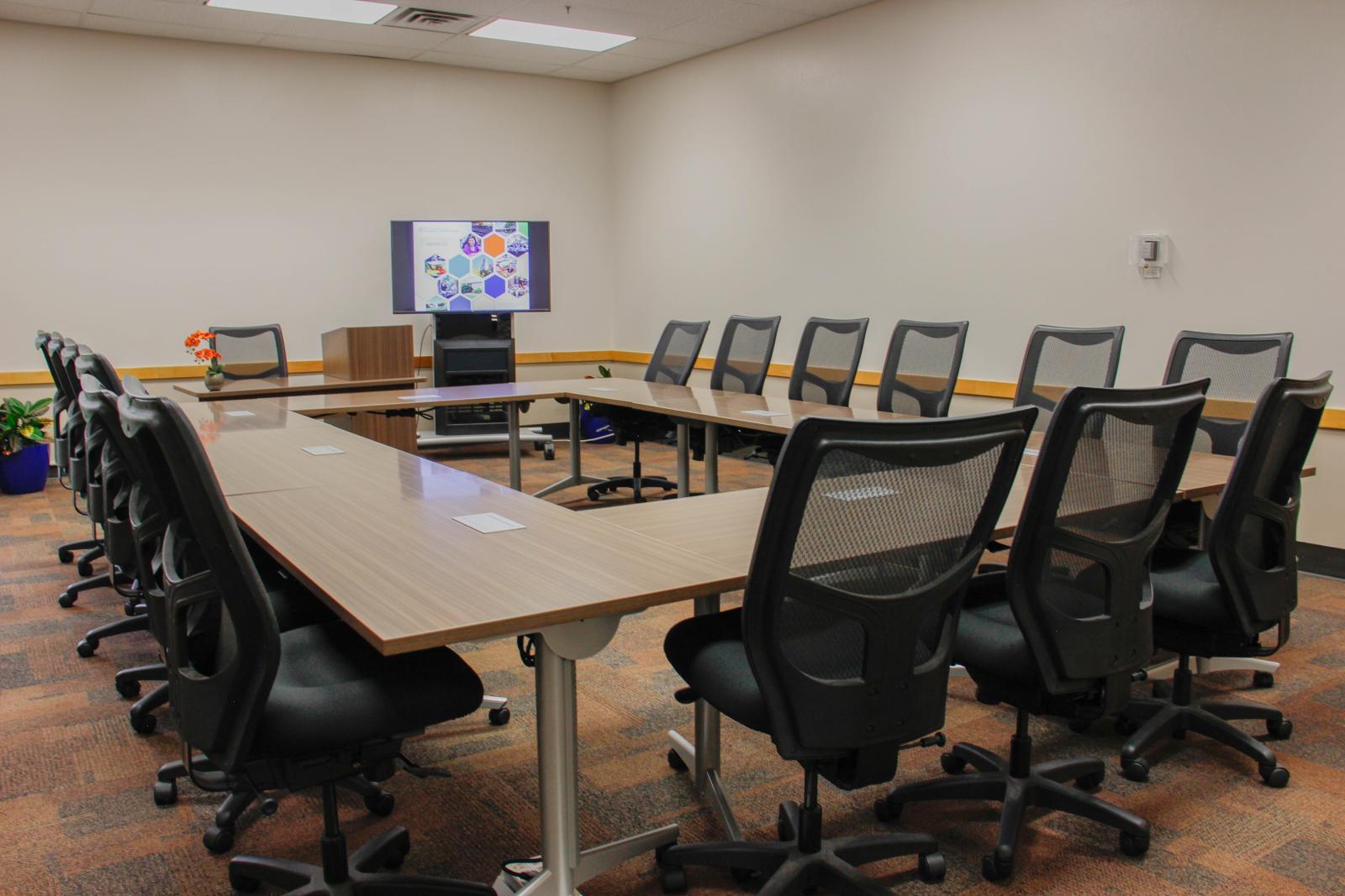 Square table with sixteen chairs in a large room.