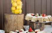 Close up of cake slices garnished with strawberries and blackberries on a catering table.
