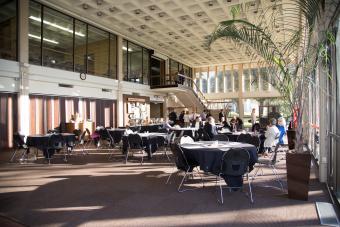 Large room with high ceilings with people sitting at tables enjoying their meals.