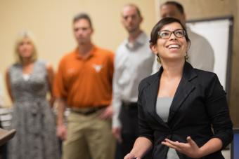 Enthusiastic woman giving a presentation with team mates at the front of the class.