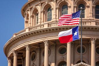Close up of Texas state Capitol with waving US flag and Texas flag