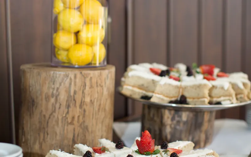 Close up of cake slices garnished with strawberries and blackberries on a catering table.